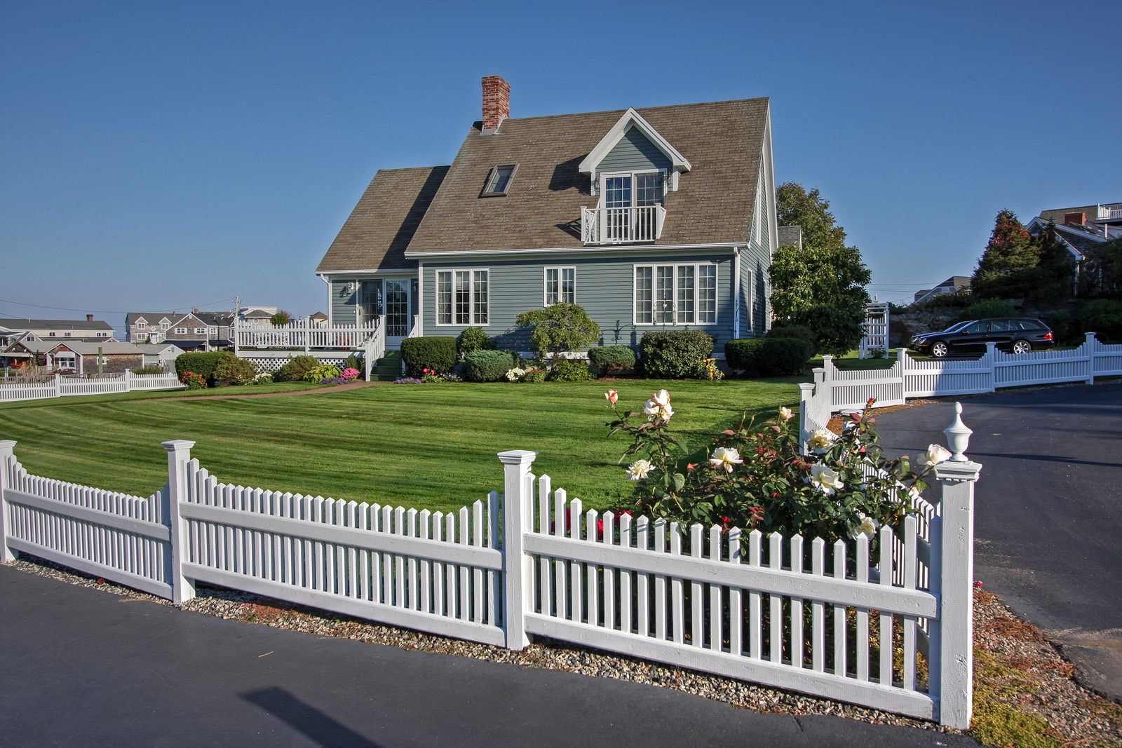 White picket fence and green lawn in front of a classic New England home
